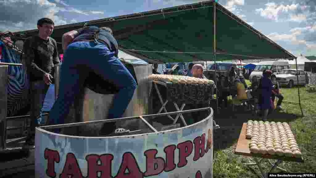 Мужчины готовятся выпекать лепешки в тандырной печи