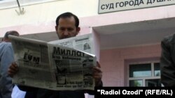 Tajikistan - a man is reading newspaper at the entrance of the court, undated