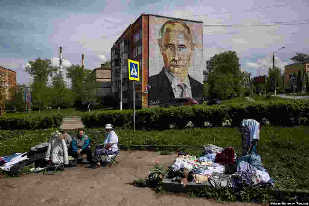 Уличные торговцы продают одежду и цветы возле многоквартирного дома с фреской с изображением президента России Владимира Путина в городе Кашира Московской области